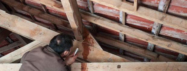 inspecting leaking roof, man with flashlight, water leaking through roof