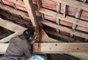 inspecting leaking roof, man with flashlight, water leaking through roof